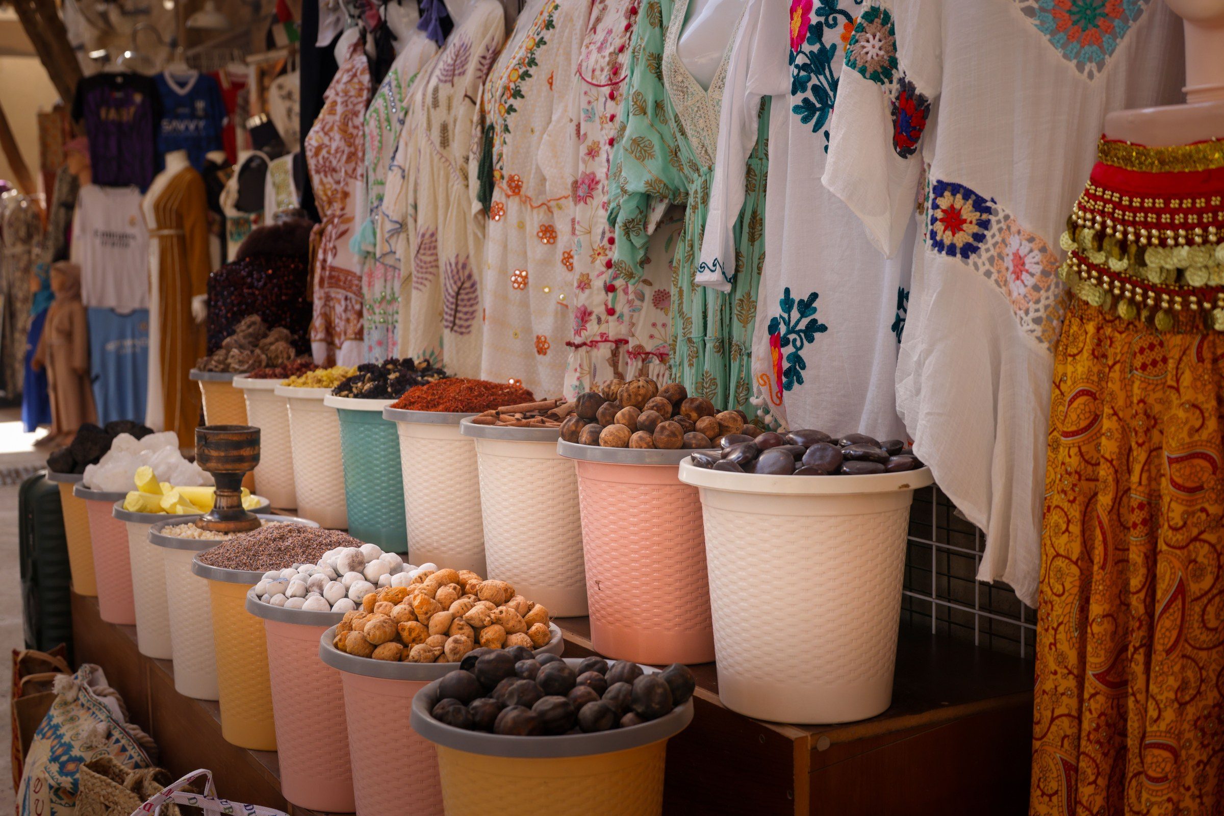 Colorful market stall showcasing traditional textiles and a variety of spices in a Middle Eastern bazaar