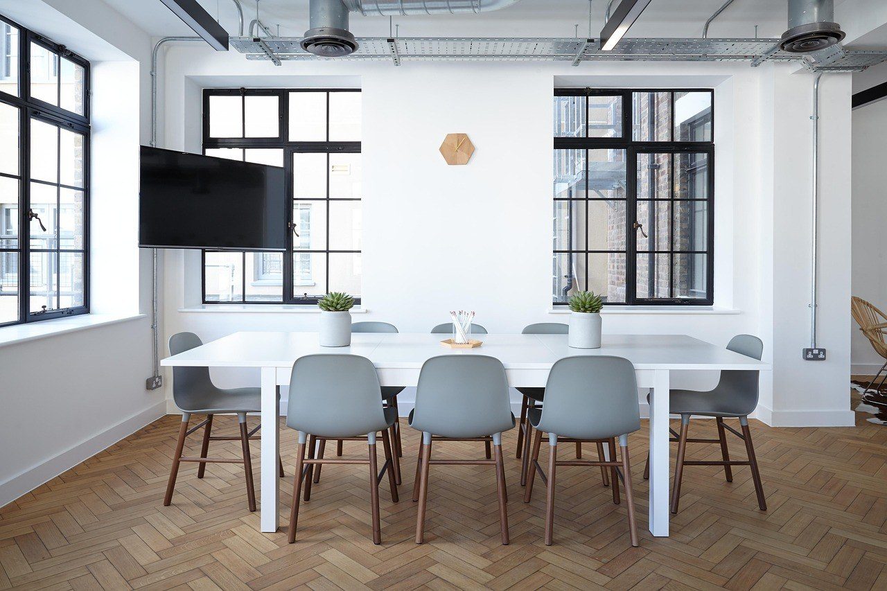 An empty meeting room with a long table and tall windows, illustrating the work of a contract lawyer in Dubai
