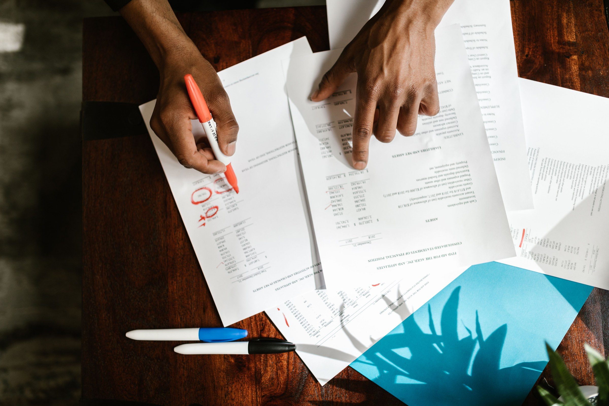 Hands marking up financial documents on a desk, illustrating company formation options in Dubai