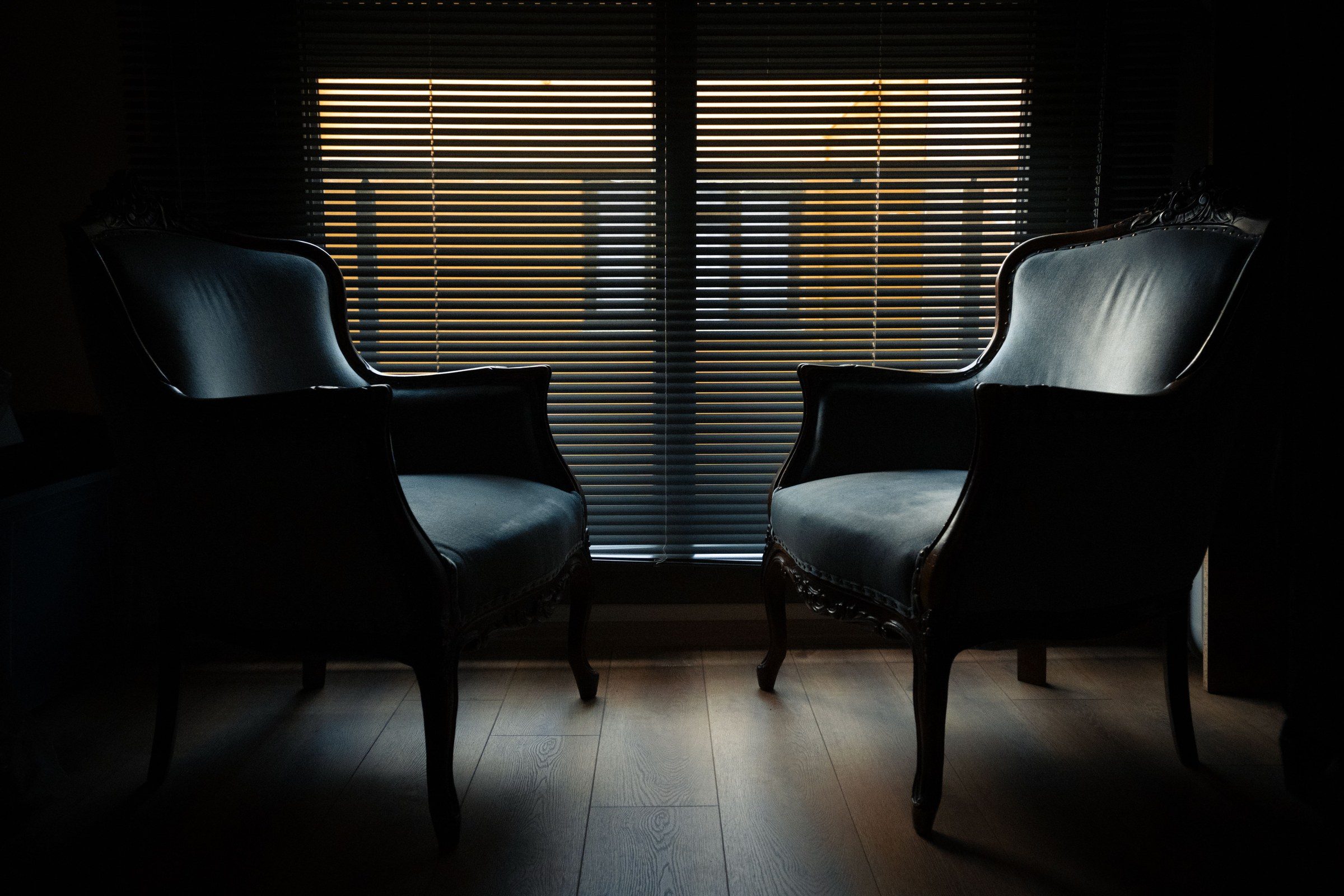 Two armchairs silhouetted against a shuttered window, illustrating the work of an arbitration lawyer in Dubai