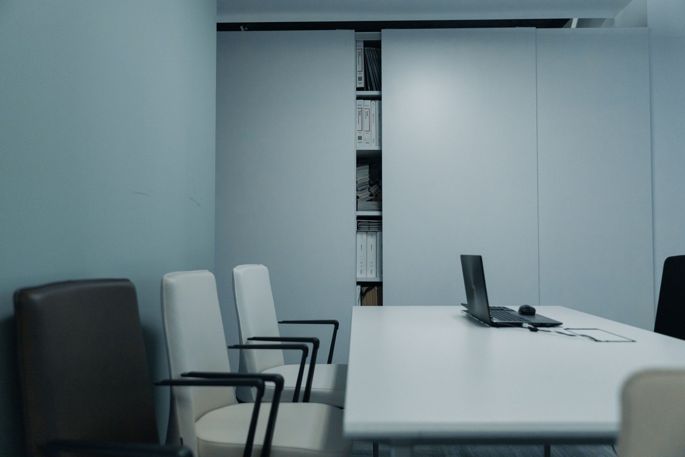 A conference room with a white table, chairs and a laptop, illustrating a law firm in Dubai