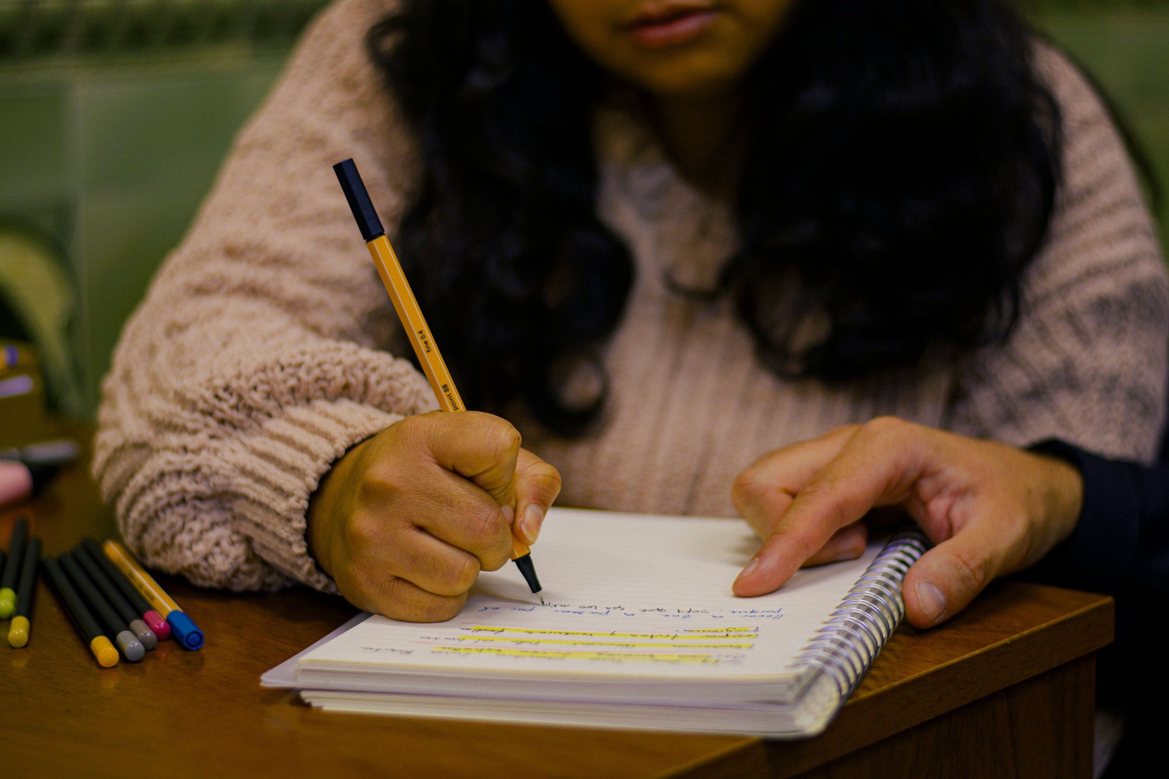 A person writing notes in a journal at a wooden desk, illustrating a free legal consultation in Dubai