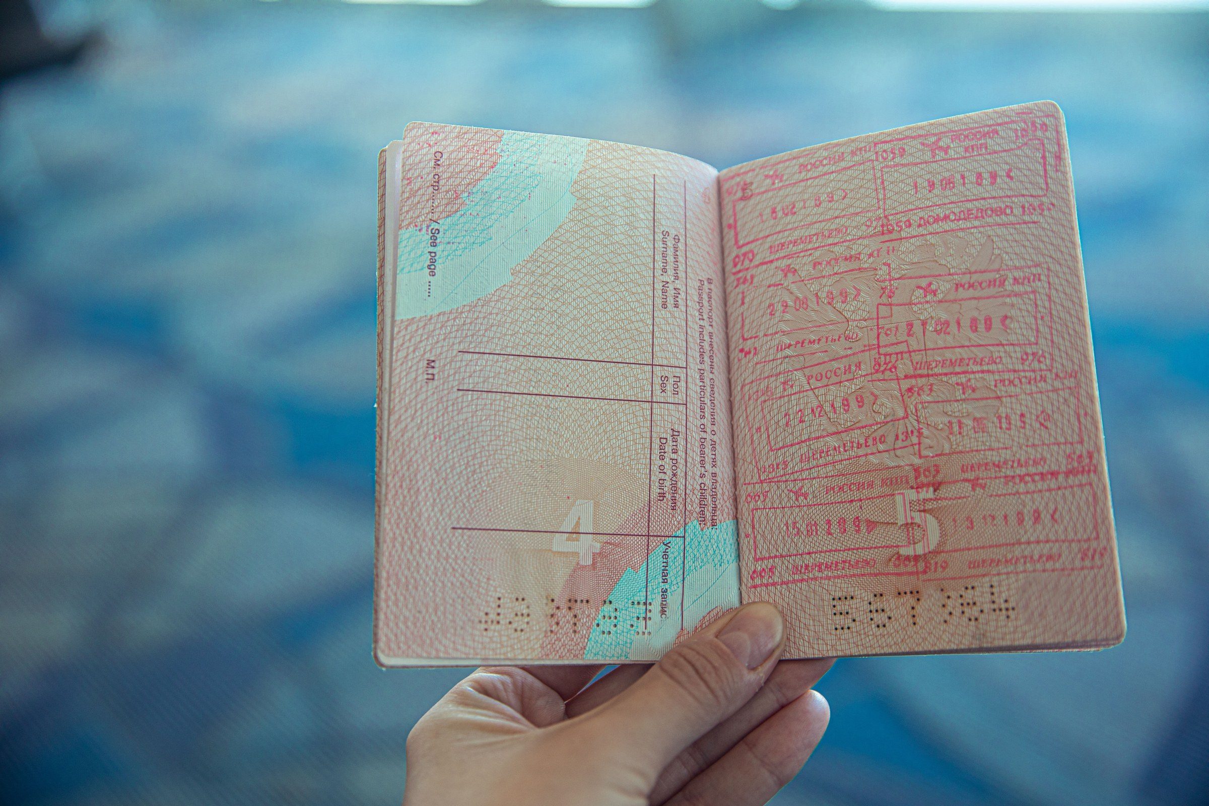 Close-up view of an open passport displaying various travel stamps in an airport setting