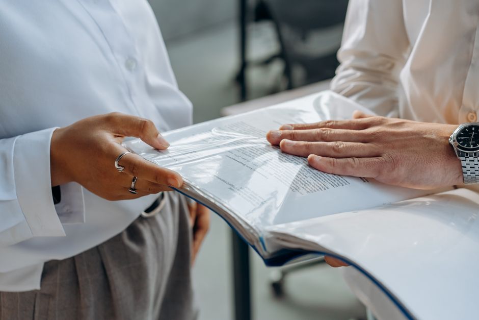 Two people examining a bound set of documents together, illustrating the work of a company formation lawyer in Dubai