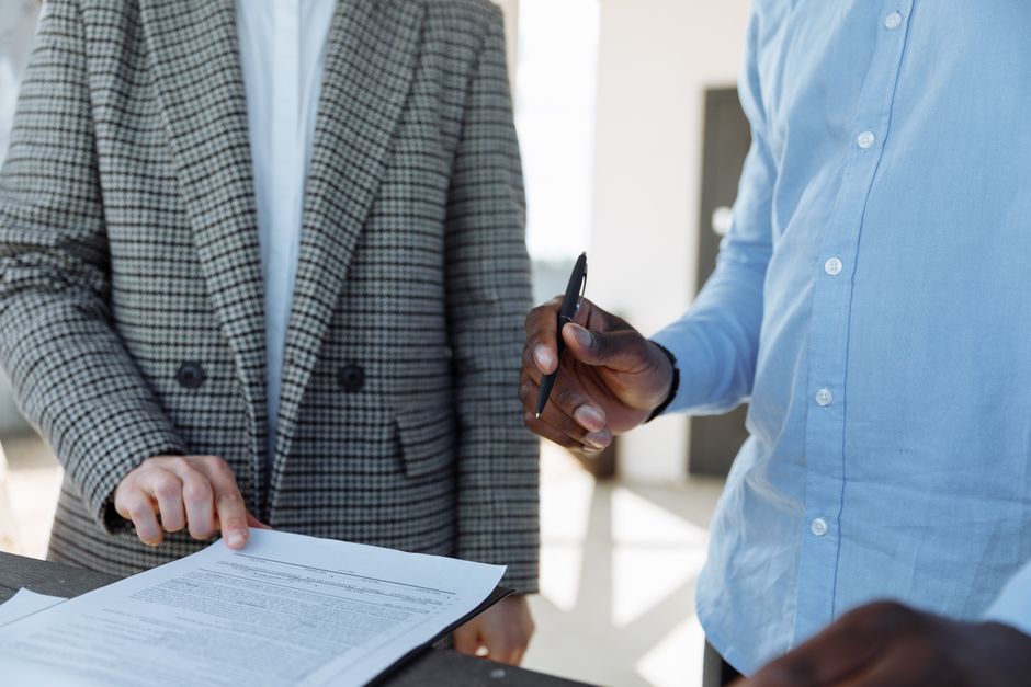 Two people standing over a printed agreement, one holding a pen, illustrating the work of a civil lawyer in Dubai