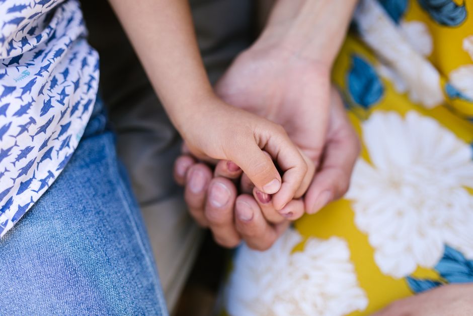 A child's hand held in an adult's hand, illustrating the work of a child custody lawyer in Dubai