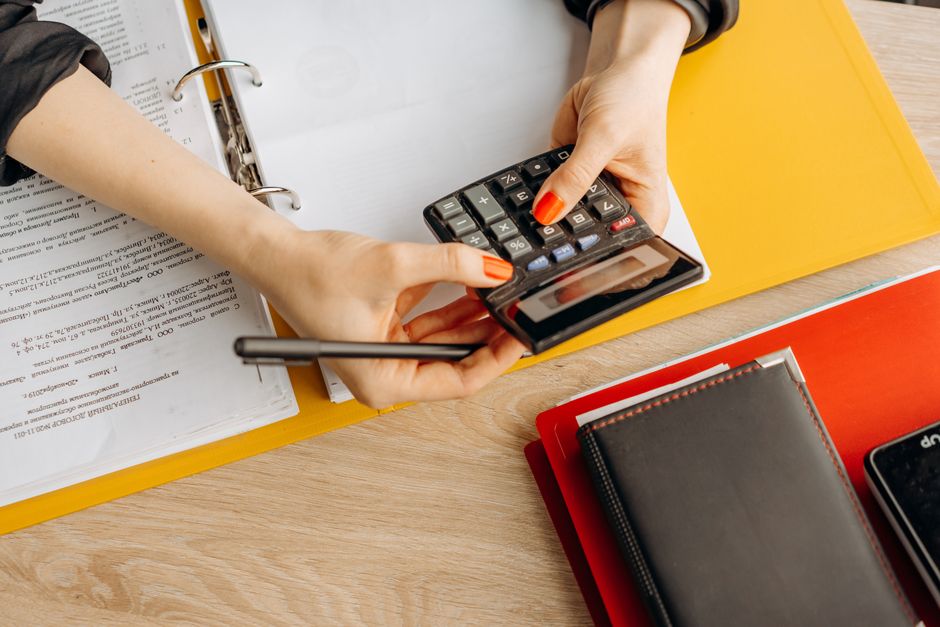 Hands working a calculator beside documents and folders, illustrating how much a divorce costs in Dubai