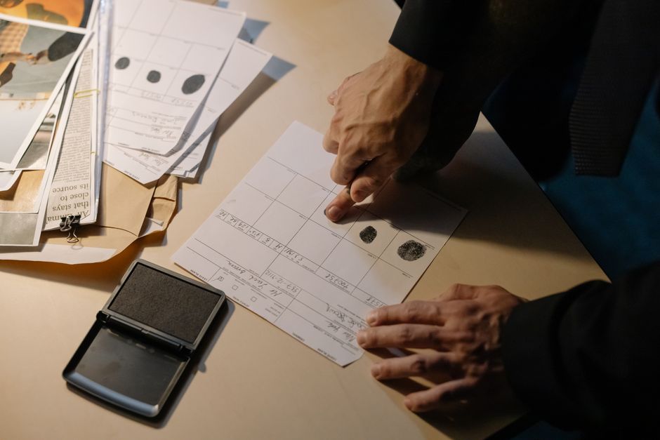 Fingerprints being taken onto a printed form beside an ink pad, illustrating the work of a police case lawyer in Dubai